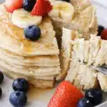 Fluffy protein pancakes with banana, strawberries, and blueberries topped with syrup
