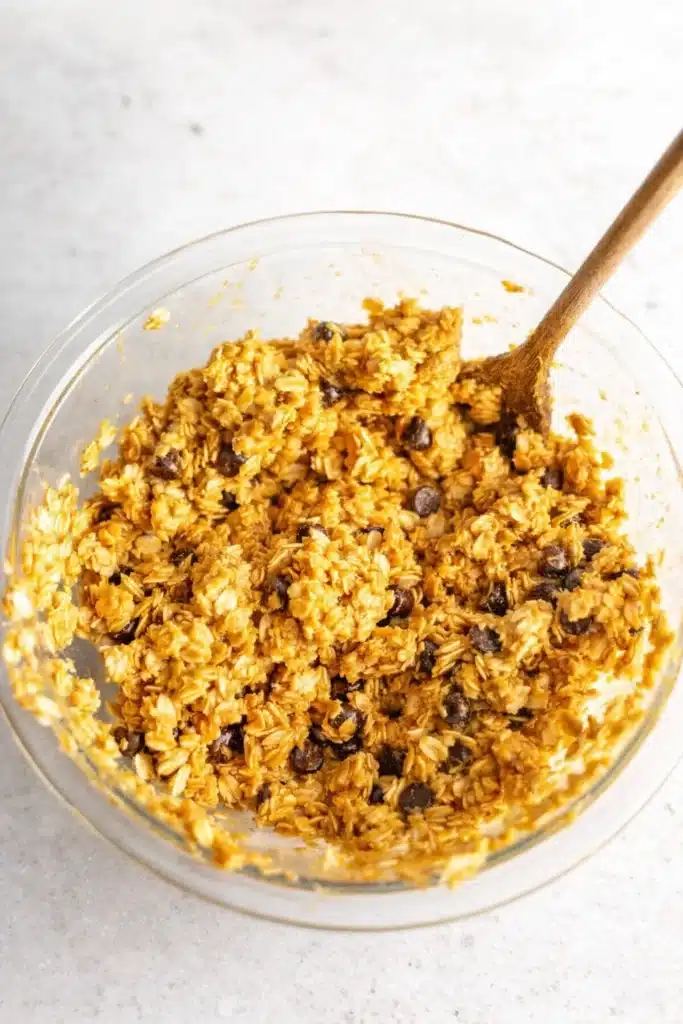 Healthy Pumpkin Oat Cookies | Easy & Delicious Treat 9 Pumpkin oat cookie dough in a glass bowl with chocolate chips and wooden spoon