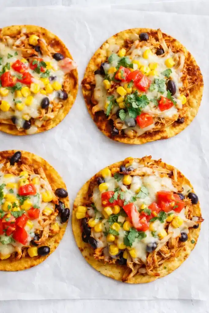 Overhead view of rotisserie chicken tostadas with cheese, corn, and cilantro