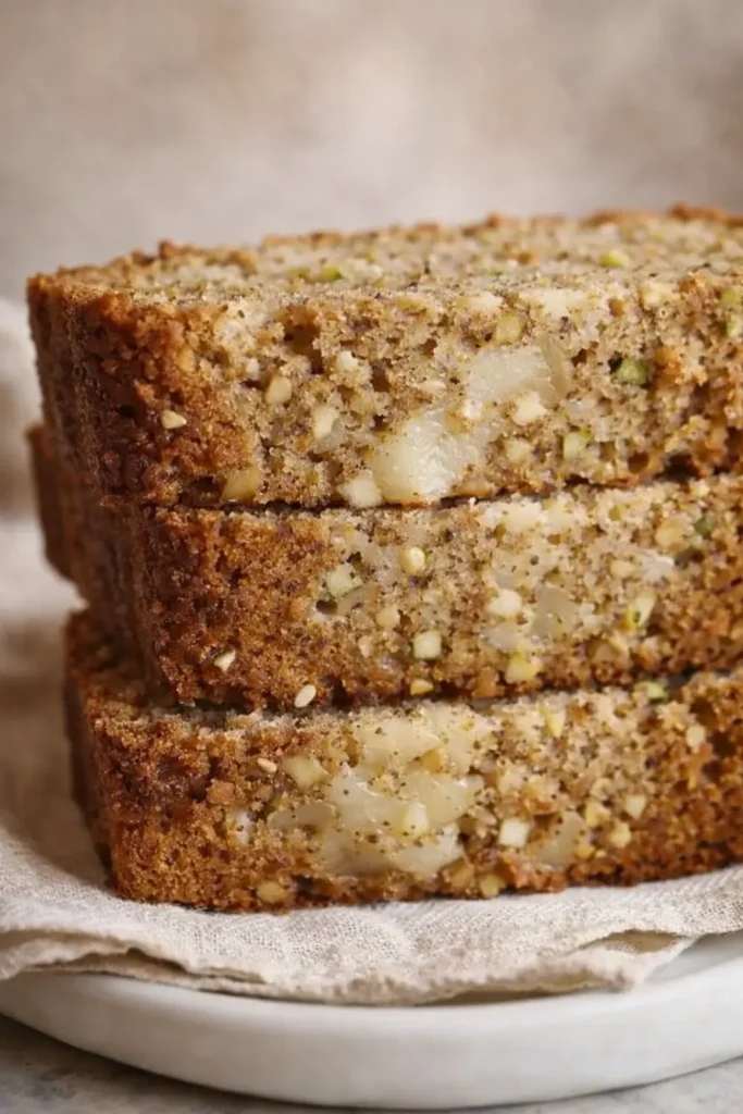 Stacked slices of cozy spiced apple zucchini bread on linen