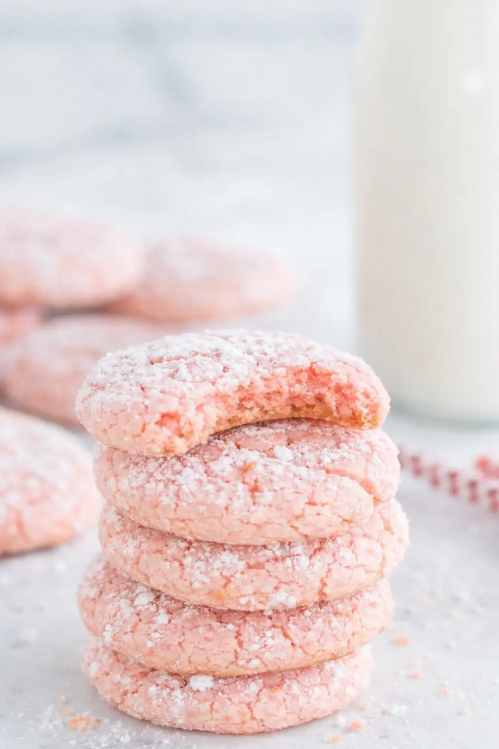 Stack of strawberry crinkle cookies dusted with powdered sugar