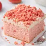 Strawberry Crunch Cake slice with frosting and crumble topping on white plate