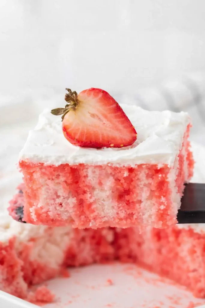 Strawberry Jello Poke Cake | Easy, Refreshing, and Delicious 5 Strawberry Jello poke cake slice lifted from pan with whipped topping