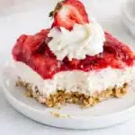 Strawberry Pretzel Salad slice with whipped cream and fresh strawberry on a plate