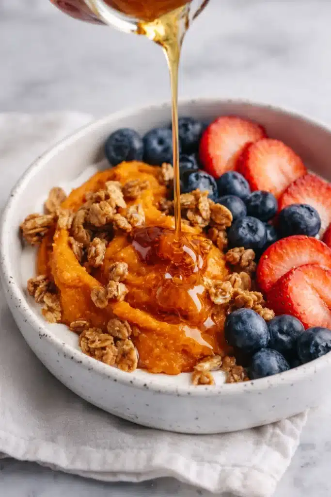 Sweet potato breakfast bowl with maple syrup, berries, and granola