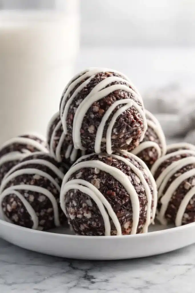 Tasty Oreo Protein Balls Recipe | Amazing No-Bake Snack 6 Tasty Oreo protein balls stacked on a white plate with white chocolate drizzle