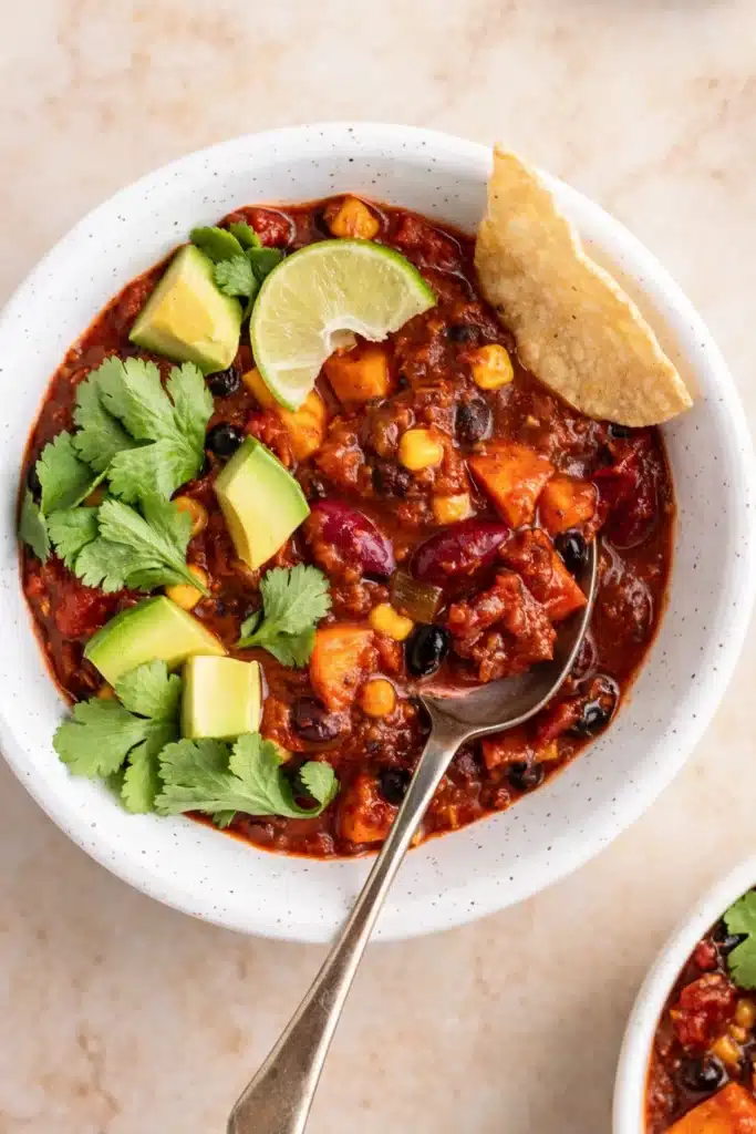 Hearty vegetarian chili with avocado, cilantro, and lime in a rustic bowl
