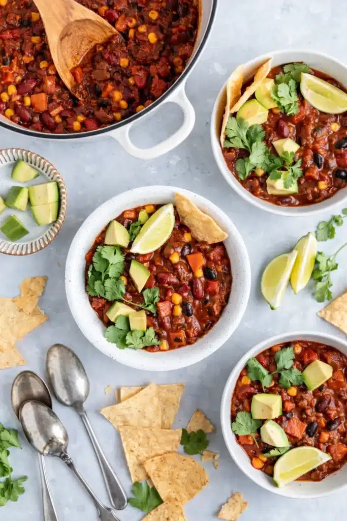 Overhead view of vegetarian chili with avocado, lime, and tortilla chips