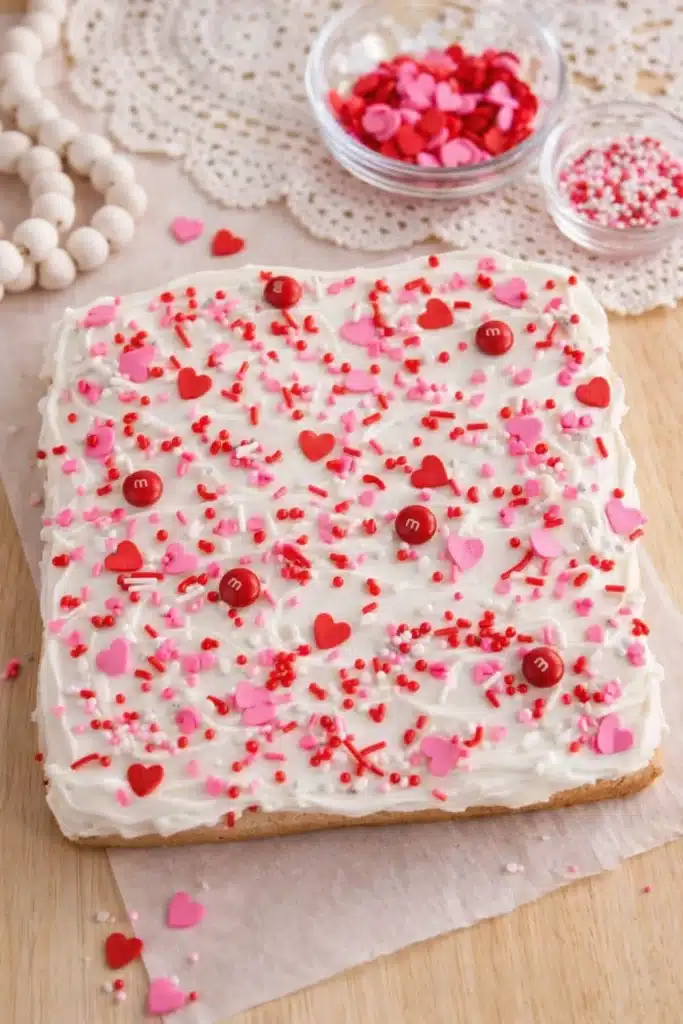Valentine sugar cookie bar topped with white frosting and heart sprinkles