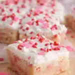 Valentine sugar cookie bar with white frosting and heart sprinkles