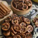 Caramelized air fryer banana slices in skillet with cinnamon sticks