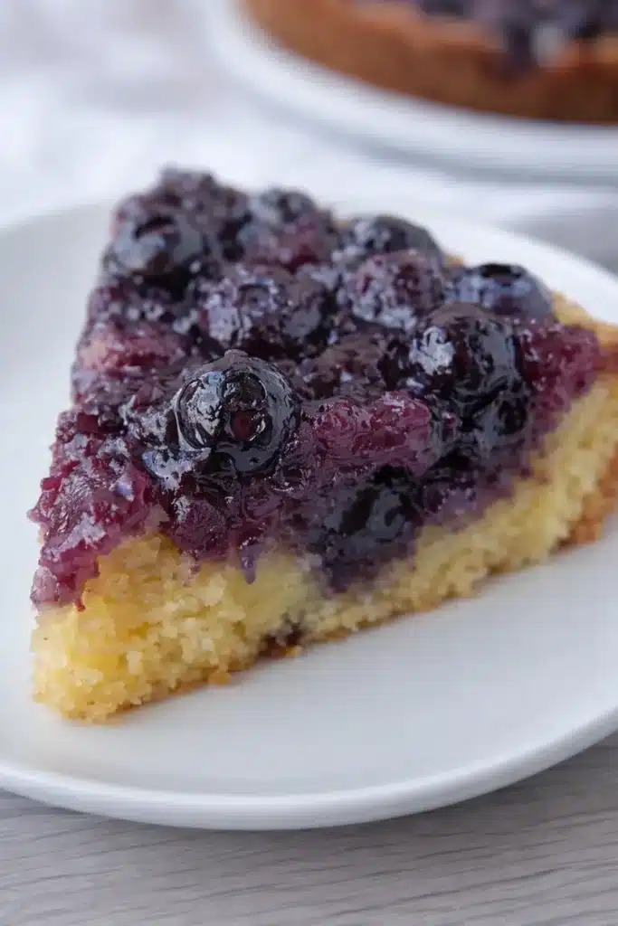 Slice of homemade blueberry upside down cake on white plate