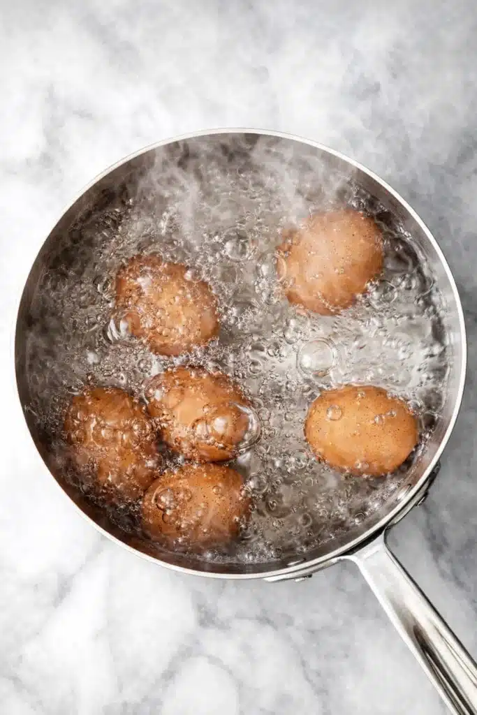 Brown eggs boiling in a stainless steel pot on marble surface