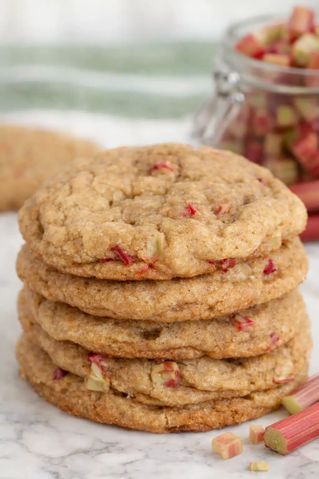 Stack of soft brown sugar rhubarb cookies with visible rhubarb pieces on marble surface