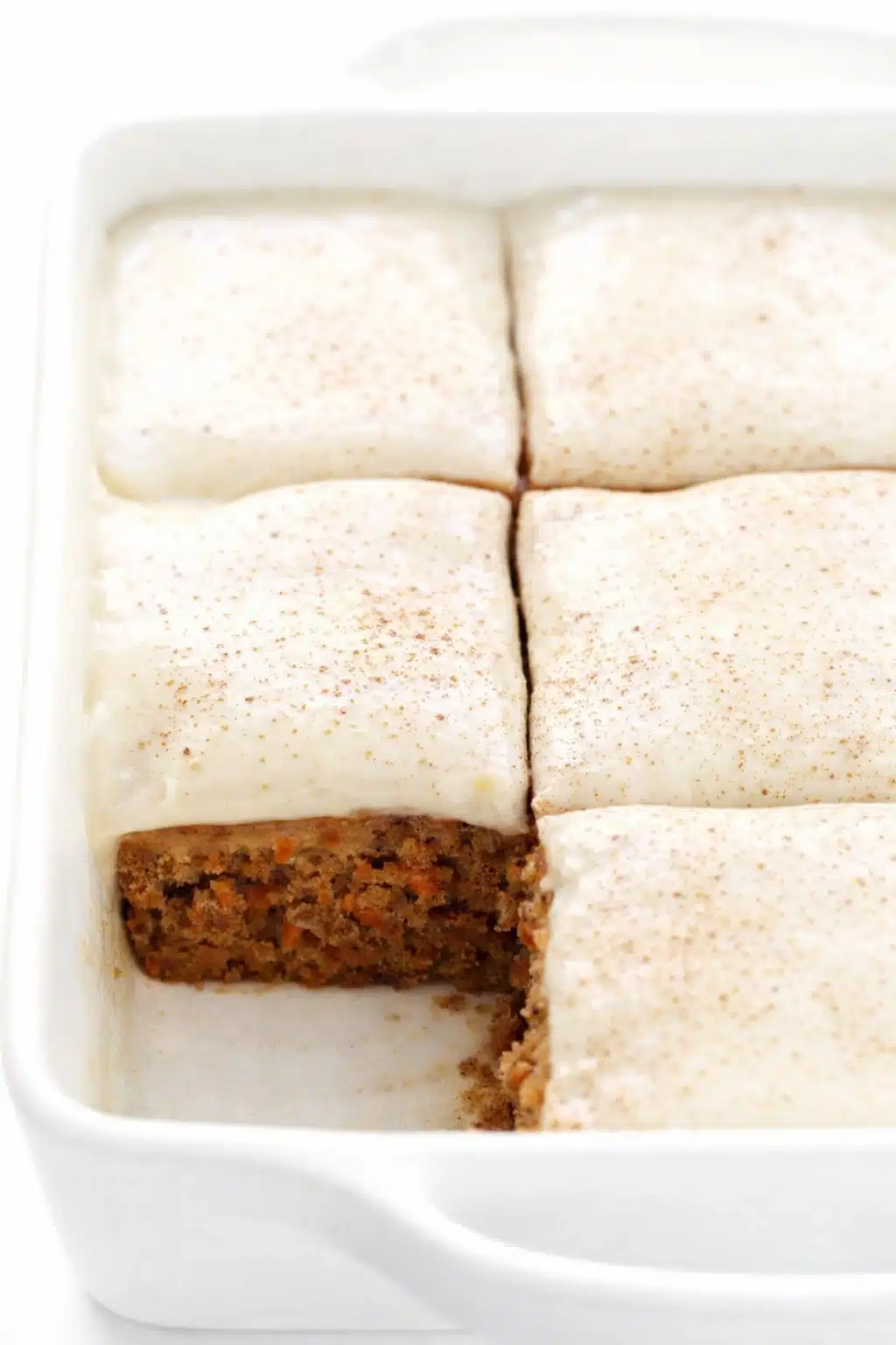 Moist carrot cake bars with cream cheese frosting and cinnamon topping in baking dish