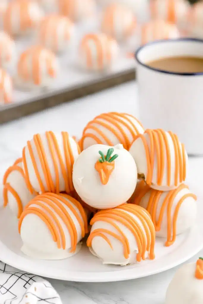 Carrot Cake Cheesecake Bites with orange drizzle and candy carrot topping on a white plate