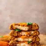 Stack of carrot cake cookies with cream cheese filling and carrot frosting
