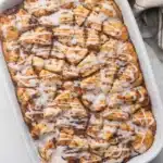 Overhead cinnamon roll casserole with vanilla glaze in white baking dish