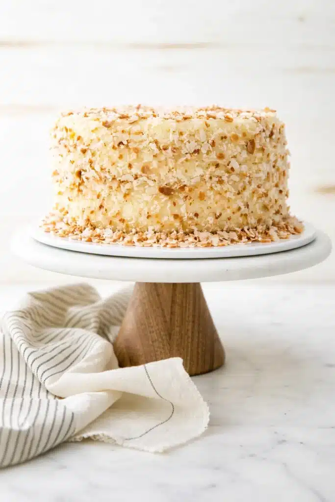 Whole coconut custard cake covered with toasted coconut on a cake stand