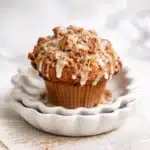 Coffee cake muffin with cinnamon streusel and vanilla glaze on ceramic plate