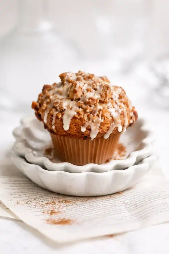 Coffee cake muffin with cinnamon streusel and vanilla glaze on ceramic plate