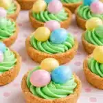 Easter basket sugar cookie cups with green frosting and pastel candy eggs