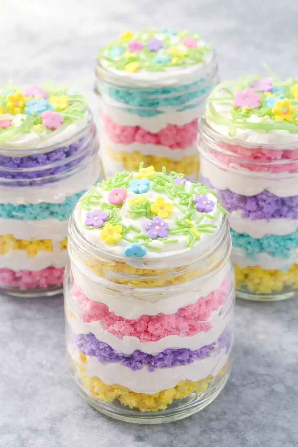 Easter cake in a jar with pastel layers and white frosting in glass jars