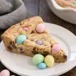 Easter cookie cake slice topped with pastel chocolate eggs on a white plate