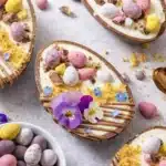 Easter egg cheesecakes with mini eggs and edible flowers on a light background