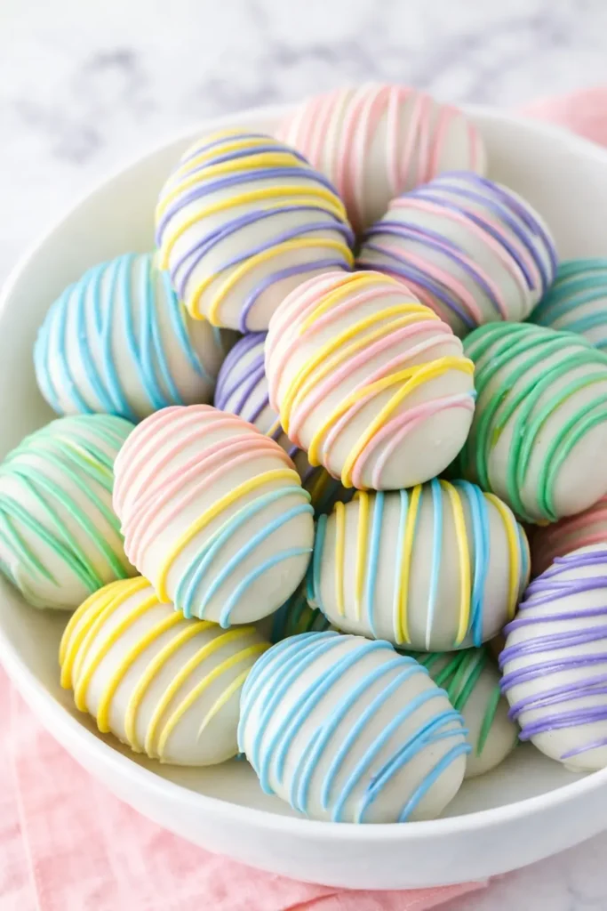 Easter Egg Oreo Cookie Balls – Easy, Fun & Delicious 8 Pastel Easter Egg Oreo Cookie Balls in a white bowl with colorful drizzle