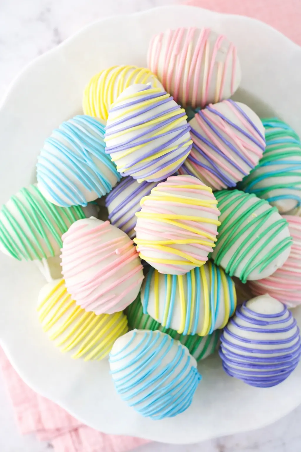 Pastel Easter Egg Oreo Cookie Balls on a white plate with colorful candy drizzle