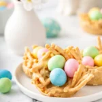 Easter Egg Peanut Butter Haystacks with pastel candy eggs on a white plate
