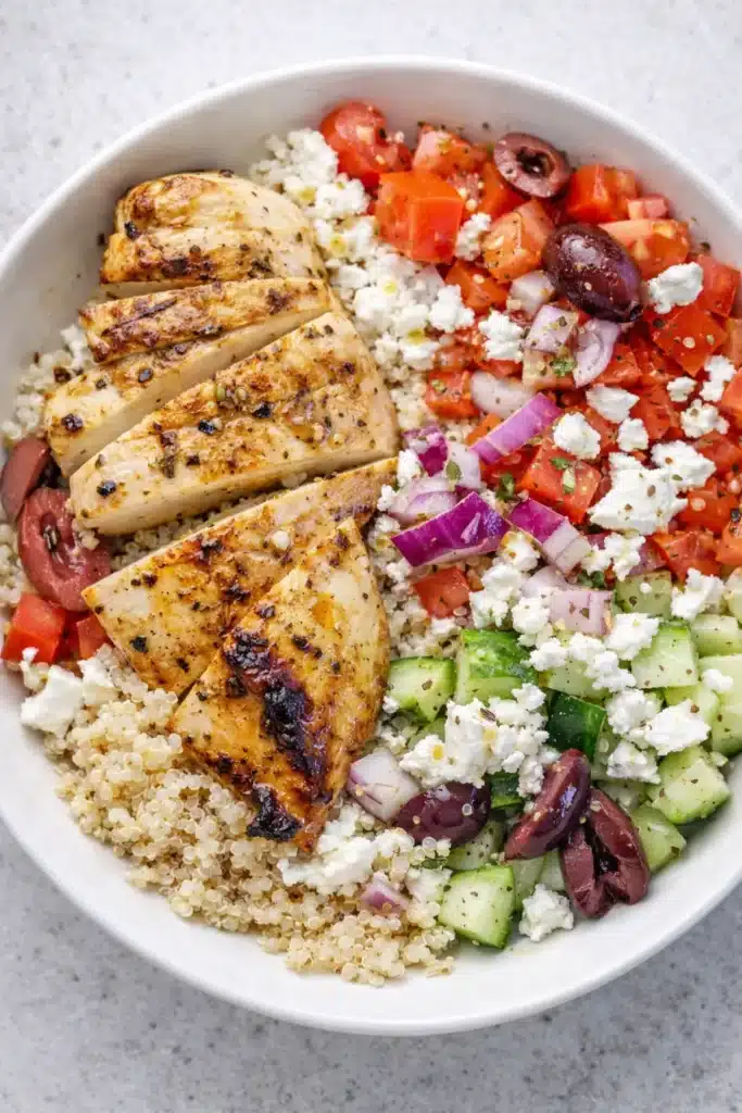 Greek chicken bowl with grilled chicken, quinoa, feta, cucumbers, tomatoes, and olives