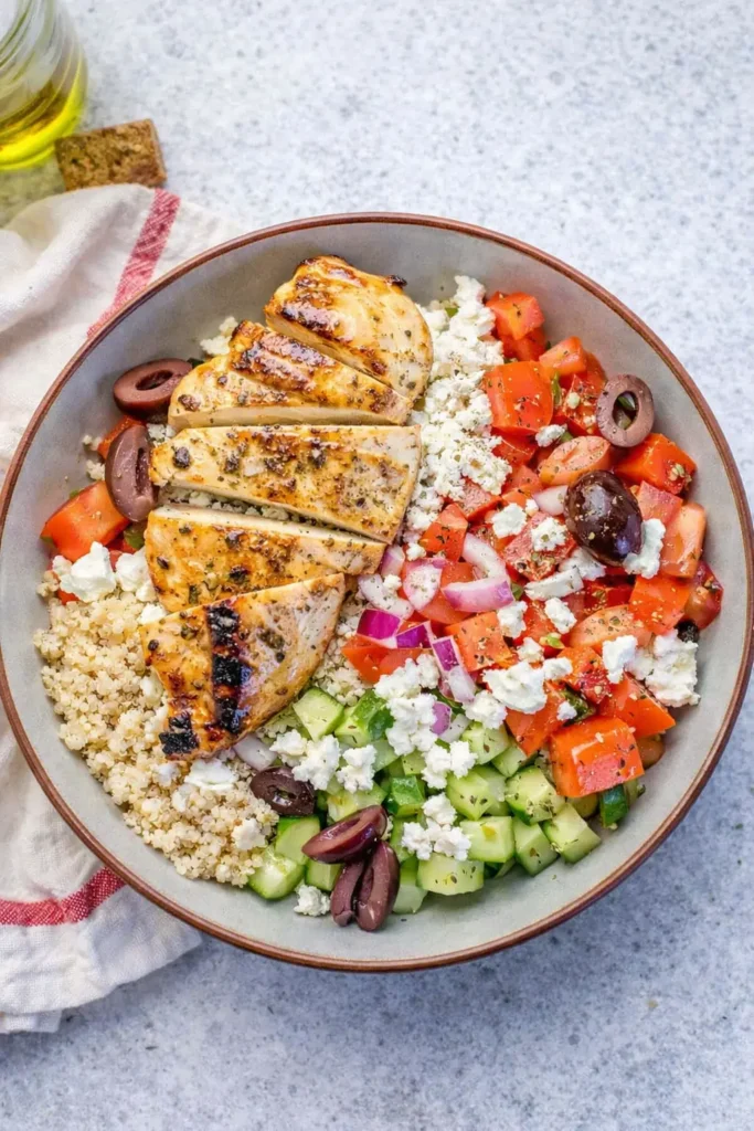 Greek chicken bowl with quinoa, grilled chicken, feta, olives, and fresh vegetables