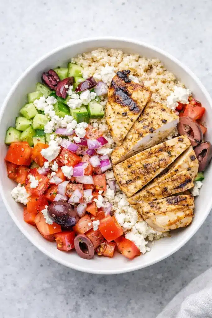 Greek chicken bowl with quinoa, grilled chicken, fresh vegetables, and feta cheese