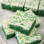 Green velvet brownies with cream cheese frosting and green sprinkles on white plate
