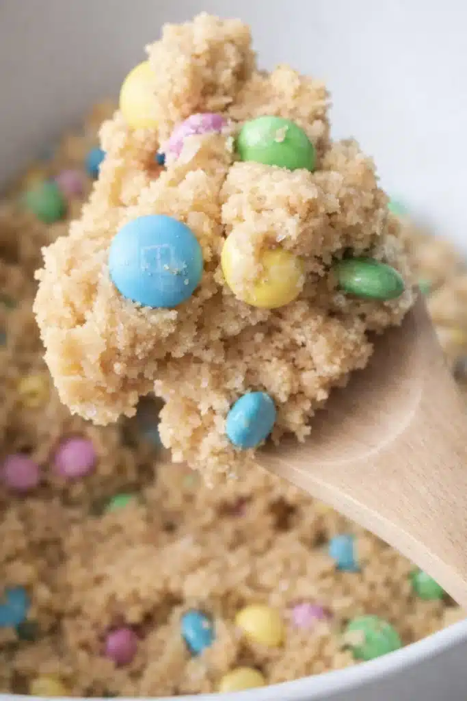 How to Make Perfectly Soft M&M Cookies That Wow 4 How to Make Perfectly Soft M&M Cookies dough with pastel candies on wooden spoon