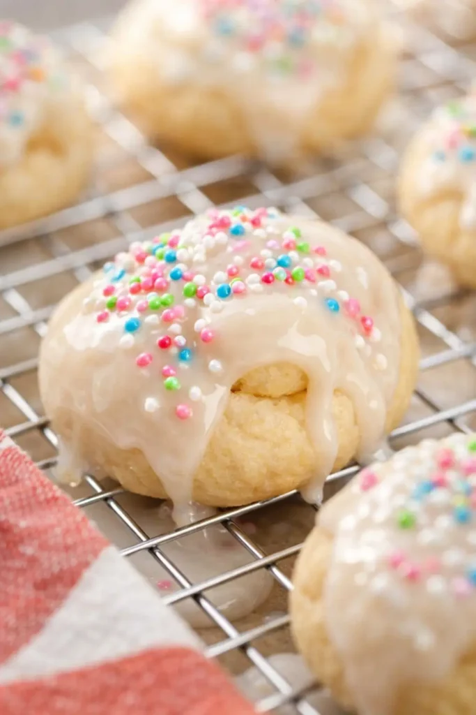 Italian Easter Cookies with white glaze and colorful sprinkles on cooling rack