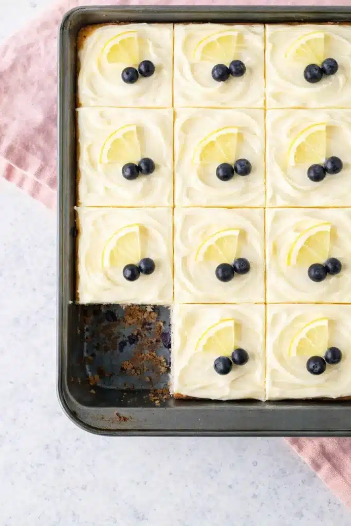 Lemon Blueberry Cake sheet slices with cream cheese frosting and lemon garnish