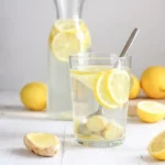 Glass of lemon ginger water with lemon slices and fresh ginger on rustic table