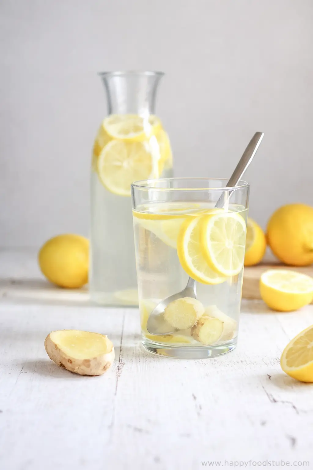 Glass of lemon ginger water with lemon slices and fresh ginger on rustic table
