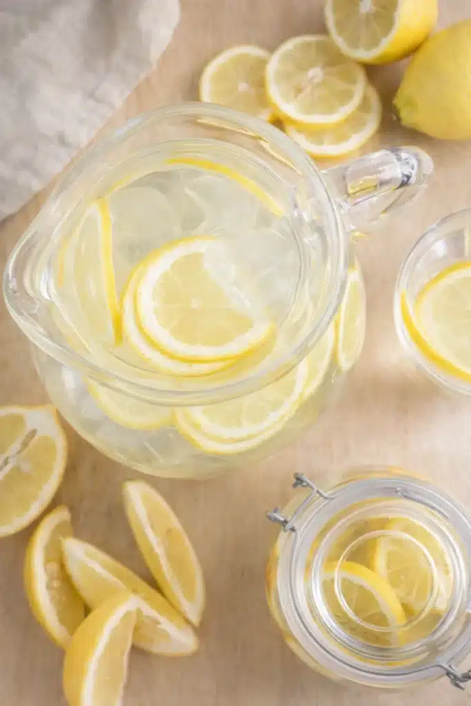 Top view of lemon water pitcher with lemon slices on wooden table