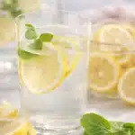 Glass of lemon water with lemon slices and mint on marble counter