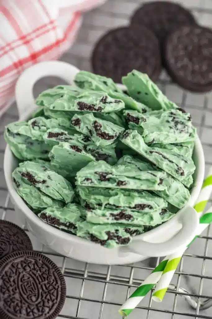 Mint Oreo Bark No Bake White Chocolate Dessert 5 Mint Oreo Bark stacked in white cup with cookie chunks