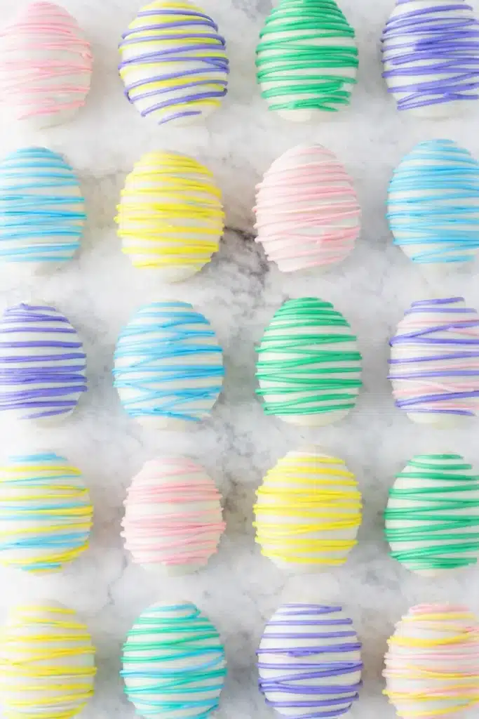 Easter Egg Oreo Cookie Balls – Easy, Fun & Delicious 7 Pastel Easter Egg Oreo Cookie Balls arranged on marble in colorful drizzles