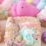 Chewy Peeps sugar cookie bar with pastel marshmallow swirls and colorful marshmallow chicks in the background.