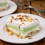 Layered pistachio lush dessert with nut crust and whipped topping