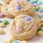 Soft pastel M&M cookies stacked on marble surface with colorful candy pieces