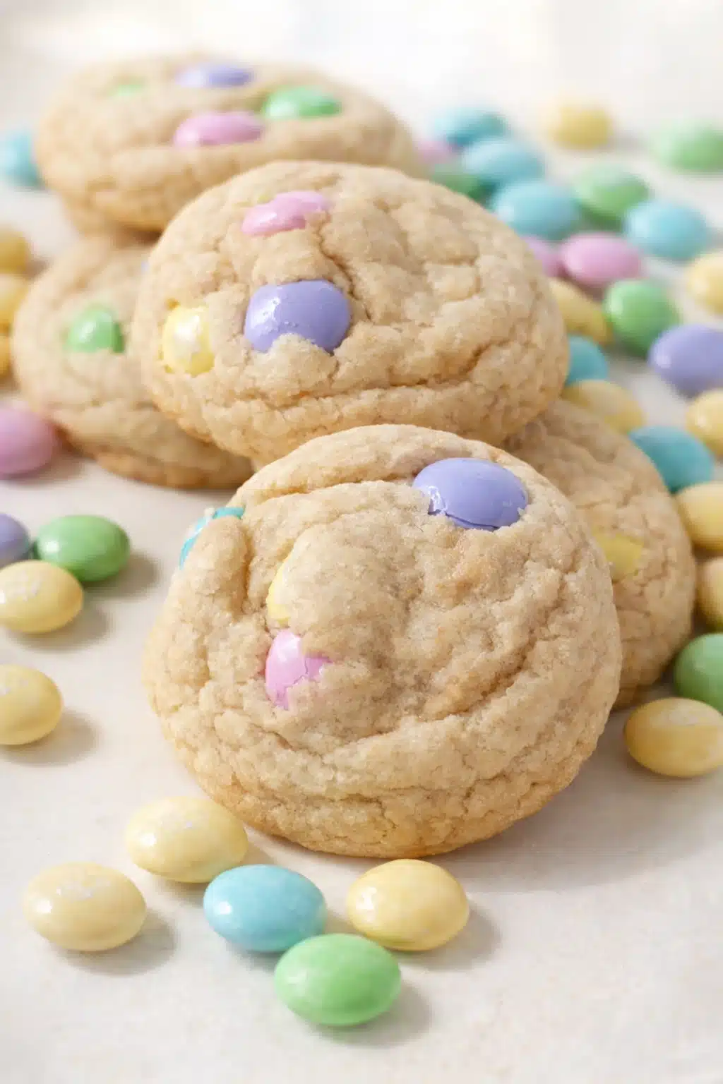 Soft pastel M&M cookies stacked on marble surface with colorful candy pieces