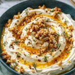 Spicy ricotta dip with hot honey, toasted nuts and rosemary in ceramic bowl